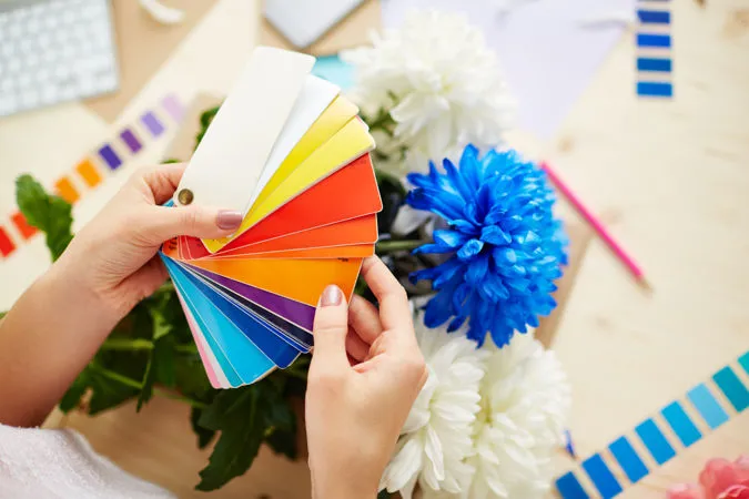 Mazzetta colori pantone in mano a una ragazza con sottofondo una scrivania da ufficio