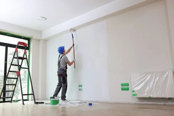 Pittore che vernicia le pareti di una casa