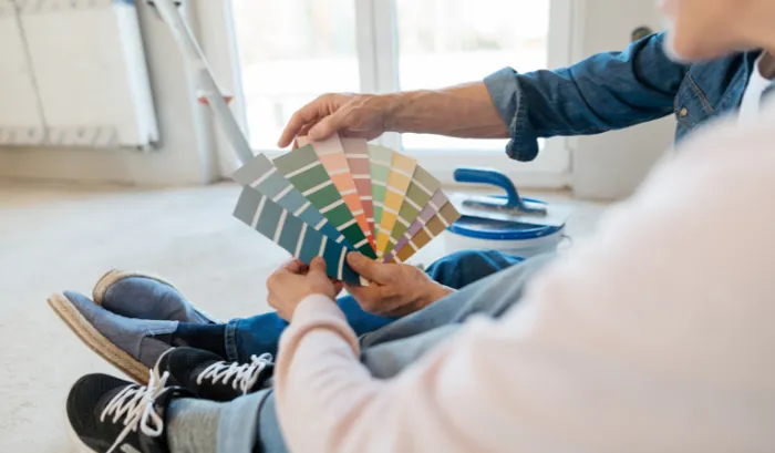 un signore e una signora che sfogliano una palette di colori per scegliere il colore delle pareti